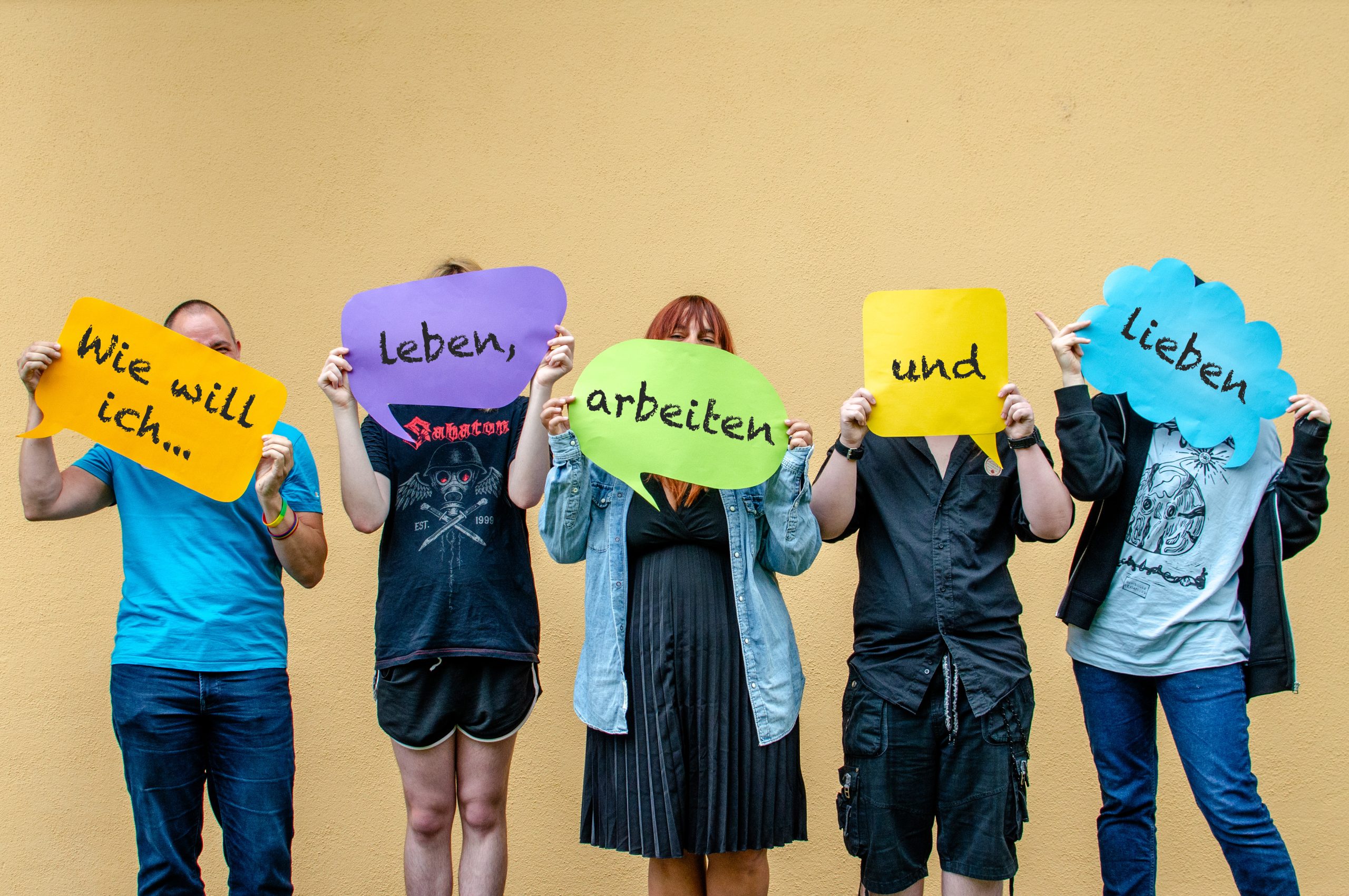 Vier Personen halten bunte Zettel mit der Aufschrift "Wie will ich leben, arbeiten und lieben"